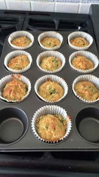 Cooked cheese and spinach muffins in a grey muffin tray